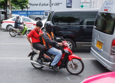 Motosiklet sürme sırasında bir akıllı telefon kullanan genç adam