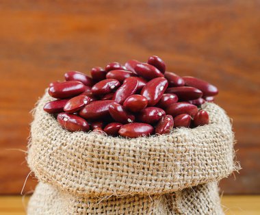 Kırmızı fasulye veya ahşap arka plan kenevir torba içinde kırmızı börülce.