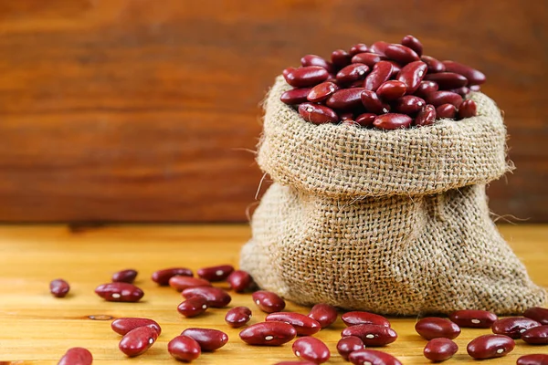 Rote Bohnen oder rote Nierenbohne im Hanfsack auf Holzgrund. — Stockfoto