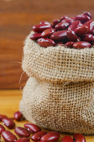 Red bean or red kidney bean in hemp sack on wooden background.