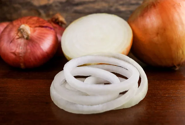 Fresh onion and onion rings on wooden background. — Stock Photo, Image