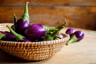 Ahşap arka plan üzerinde sepet içinde taze mini mor patlıcan