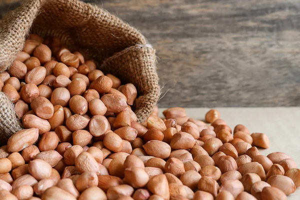 Erdnüsse im Hanfsack auf Holzgrund — Stockfoto