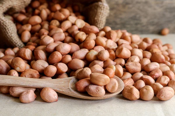 Erdnüsse im Hanfsack auf Holzgrund — Stockfoto