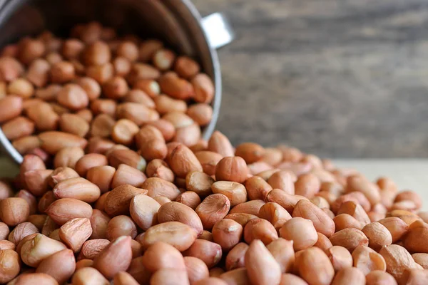 Erdnüsse im Edelstahlbecher auf Holzgrund. — Stockfoto