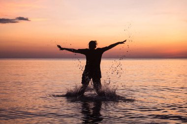 Genç kadınlar tropikal sahilde eğleniyor özgürce kollarını açıp su sıçratıyorlar. Seyahat tatilinde güzel bir yaz günü..