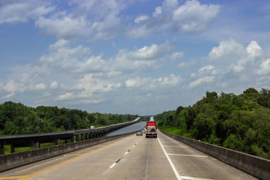 Kaldırımlı geniş bir yol, ormanın ortasında arabaların bir yaz günü geçtiği büyük yüksek köprüler. Louisiana 'daki Büyük Köprüler, Usa