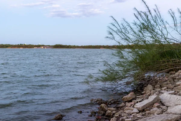 A large lake, the banks are strewn with huge stones. On the lake on a summer evening. Lake Casa Blanca, Texas, USA