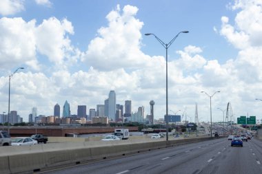 Şehir manzarası bir yaz günü - otoyolda arabalar var, gökdelenler uzaktan görülebiliyor, güneş parlıyor
