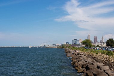 Gölün kayalık kıyılarını tasvir eden güzel yaz manzarası, sudaki dalgalar ve uzaktaki gökdelenlerin acıları. Cleveland, Ohio manzaralı, Erie Gölü 'nden Usa