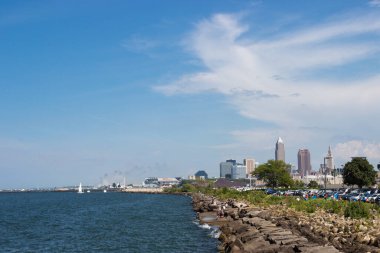 Gölün kayalık kıyılarını tasvir eden güzel yaz manzarası, sudaki dalgalar ve uzaktaki gökdelenlerin acıları. Cleveland, Ohio manzaralı, Erie Gölü 'nden Usa