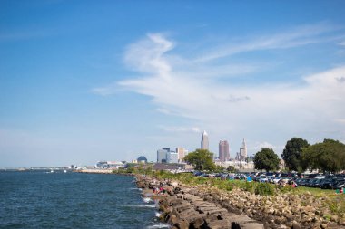 Gölün kayalık kıyılarını tasvir eden güzel yaz manzarası, sudaki dalgalar ve uzaktaki gökdelenlerin acıları. Cleveland, Ohio manzaralı, Erie Gölü 'nden Usa