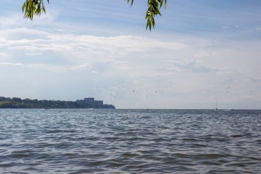 Üzerinde martıların uçtuğu bir gölet olan yaz manzarası ufukta binalar görünüyor. Erie Gölü, Cleveland, Ohio, ABD