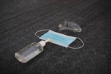 Coronavirus (covid-19) önleme ekipmanı. Tıbbi malzemeler. Gri asfaltta vücut sağlığı. Gri arka planda maske, dezenfektan ve gözlük