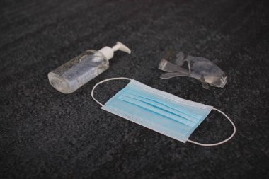 Coronavirus (covid-19) önleme ekipmanı. Tıbbi malzemeler. Gri asfaltta vücut sağlığı. Gri arka planda maske, dezenfektan ve gözlük