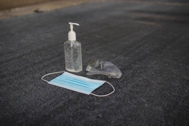 Coronavirus (covid-19) önleme ekipmanı. Tıbbi malzemeler. Gri asfaltta vücut sağlığı. Gri arka planda maske, dezenfektan ve gözlük