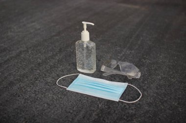 Coronavirus (covid-19) önleme ekipmanı. Tıbbi malzemeler. Gri asfaltta vücut sağlığı. Gri arka planda maske, dezenfektan ve gözlük