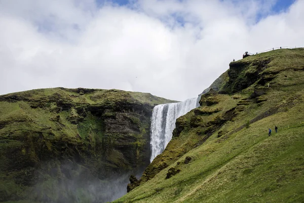 Turistas caminhando perto da cachoeira Skogafoss — Fotografia de Stock