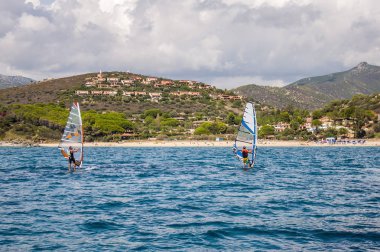İtalya iki adam Rüzgar Sörfü Sardunya kayalık sahil önünde mavi su