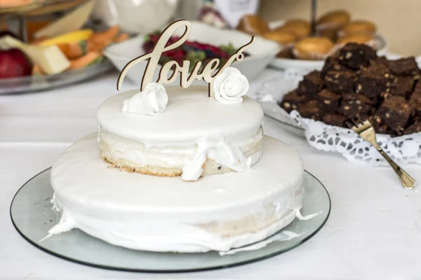 Hermosa torta de boda con crema Con texto Amor en la parte superior flores blancas rosas — Foto de Stock