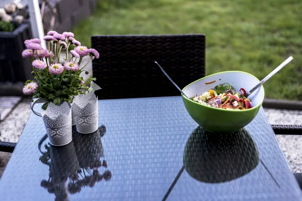 Delicioso fresco saudável salada verde tigela com comida de colher de salada de pé sobre uma mesa com flores — Fotografia de Stock