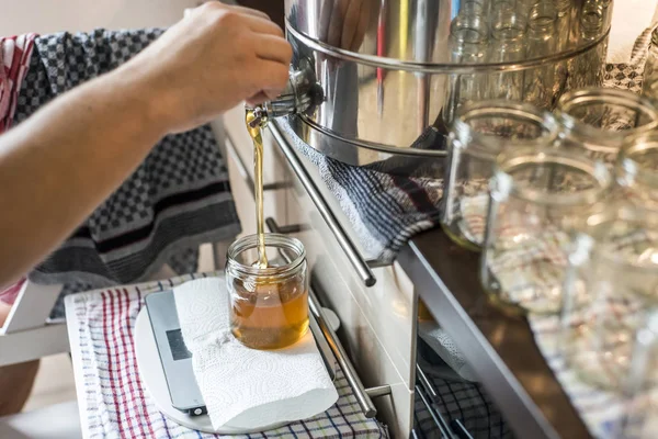 Apicultor llenando la nueva miel fresca dorada en frascos de cristal en una escala de escamas —  Fotos de Stock
