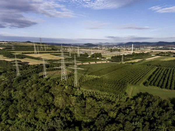 Высоковольтный металлический столб. Высоковольтная башня Вид сверху на зеленые плантации фруктов — стоковое фото
