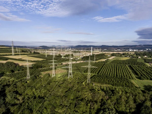 Letecký pohled na vysoké napětí kovů zaúčtovat. Produkují vysokonapěťové věž pohled shora zelené krajiny strom plaantage ovoce — Stock fotografie