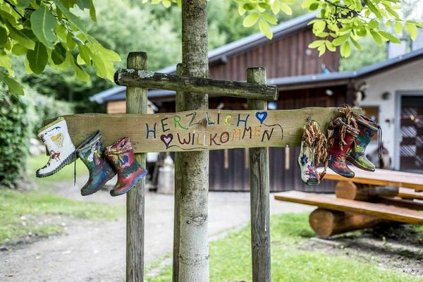 Party Label rubber boots sign wooden, forest tree house Herzlich Willkommen Means Welcome — Stock Photo, Image