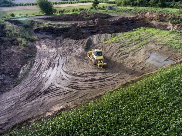 Vista superior máquina pesada escavadeira bagger trabalhando na lama no local de construção com paisagem verde circundante — Fotografia de Stock