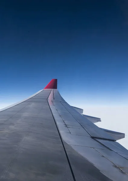 Vleugel van een vliegtuig uit de lucht in de hemel winglet rood gekleurde luchtvaartmaatschappij blauwe hemel wolken — Stockfoto