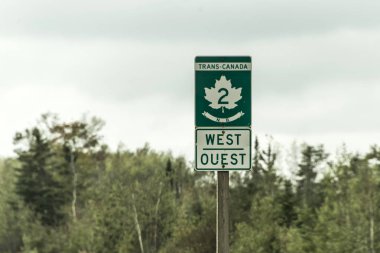 Signpost with green sign of Trans Canada 2 Highway west direction connecting the east- and west coast clipart