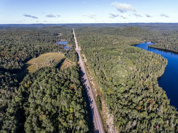 Hermoso Canadá autocaravana autobús de conducción en la carretera interminable bosque de pinos con lagos páramo tierra vista aérea fondo de viaje —  Fotos de Stock