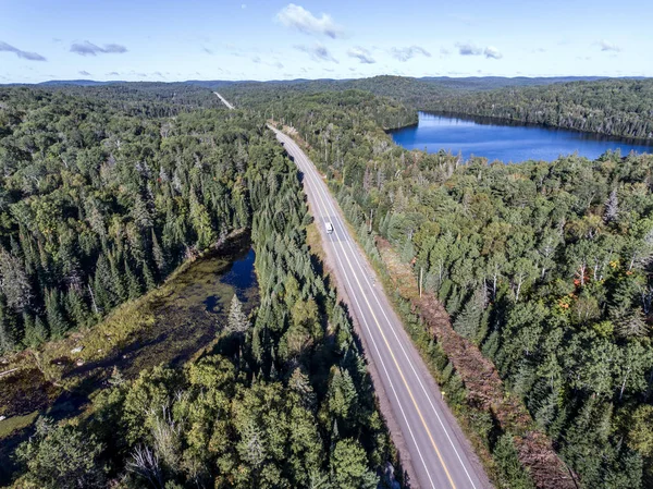 Hermoso Canadá autocaravana autobús de conducción en la carretera interminable bosque de pinos con lagos páramo tierra vista aérea fondo de viaje —  Fotos de Stock