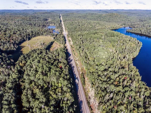 Hermoso Canadá autocaravana autobús de conducción en la carretera interminable bosque de pinos con lagos páramo tierra vista aérea fondo de viaje —  Fotos de Stock