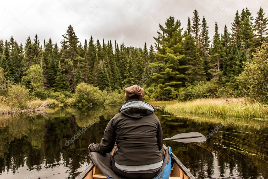 Girl canoeing with Canoe on the lake of two rivers in the algonquin national park in Ontario Canada on cloudy day