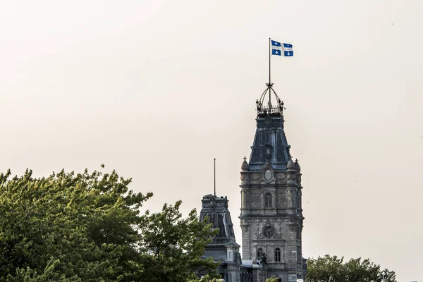 Городской флаг QUEBEC CANADA с гордостью стоит на вершине часовой башни здания парламента Квебека — стоковое фото