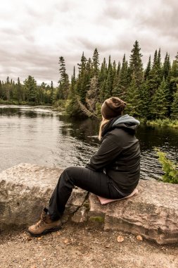 İki nehir Algonquin Milli Parkı Kanada Ontario doğal pinetree peyzaj gölün yakınında oturan kız