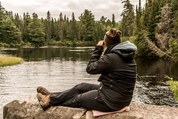 Girl with binocular sitting near Lake of two rivers in Algonquin National Park Canada Ontario natural pinetree landscape — Stock Photo, Image