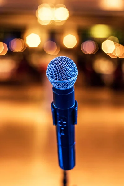 Primer plano del micrófono en concierto o sala de conferencias con luces borrosas en el fondo — Foto de Stock