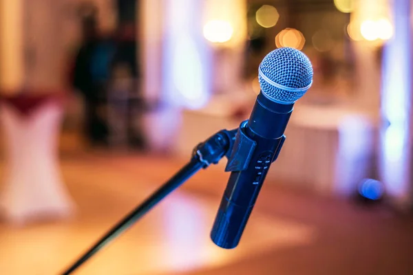 Close-up de microfone em sala de concerto ou conferência com luzes embaçadas no fundo — Fotografia de Stock