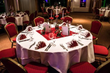 Kırmızı tablo ayarını beyaz masa örtüsü yemekleri gümüş çatal bıçak takımı gözlük ve süslemeleri beyaz kopya metin alanı kartı ile Ziyafet