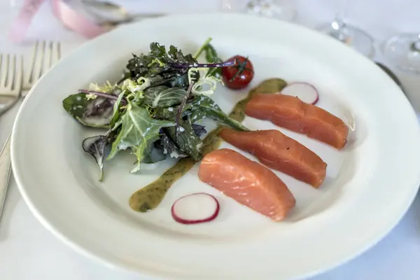 White dinner plate with salmon steak and salad on a wedding meal