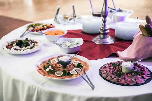 Разнообразие свежих салатов тарелки говядины и лосося на стол бизнес-ужин — стоковое фото
