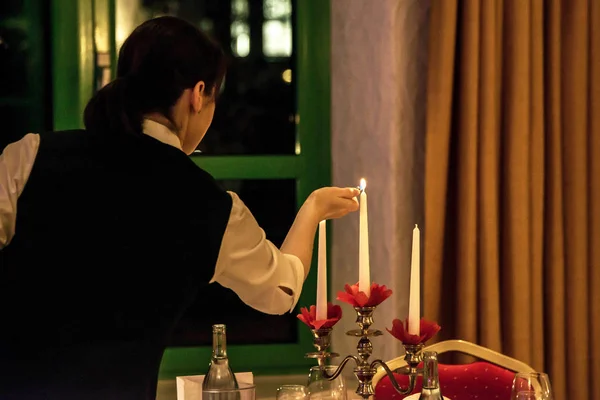 Mujer velas relámpago en banquete con ajuste de mesa roja — Foto de Stock
