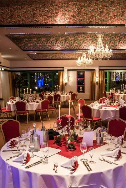 Banquete con mesa roja ajuste mantel platos blancos cubiertos de plata vasos y decoraciones copia blanca tarjeta de espacio de texto — Foto de Stock