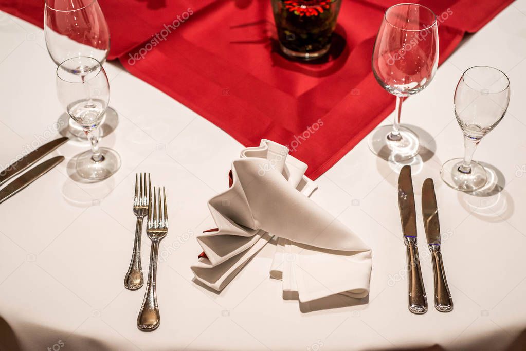 Banquet with red table setting tablecloth white dishes silver cutlery glasses and decorations white copy text space card