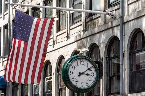 Boston, MA USA - Shopping Mall Store front with american flag waving with a big clock beside it — Stock Photo, Image