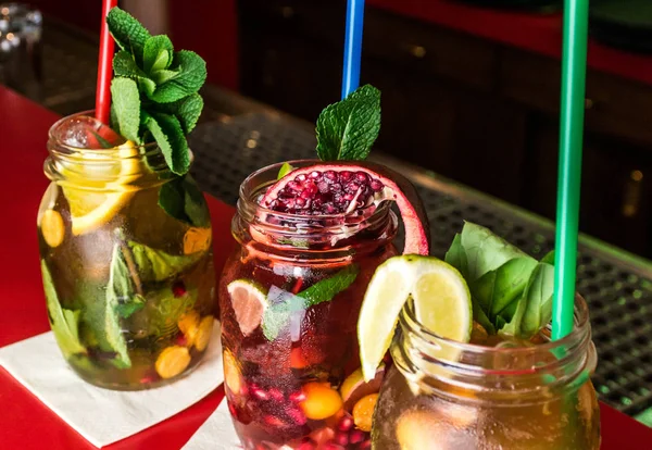 Hausgemachter Limonade Eistee buntes Eistee-Getränk mit frischen süßen Früchten Minzblätter im Glas auf den Felsen mit Stroh — Stockfoto