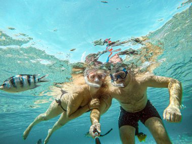 Genç çift, Mısır Okyanusu 'ndaki mercan resifinde su altında selfie çekiyorlar. Hurghada seyahat konsepti tatili.